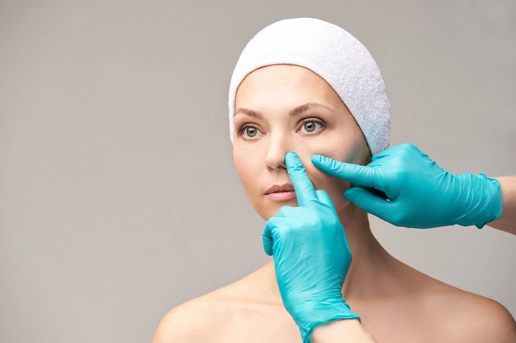 Clinician assessing nose during a rhinoplasty consultation